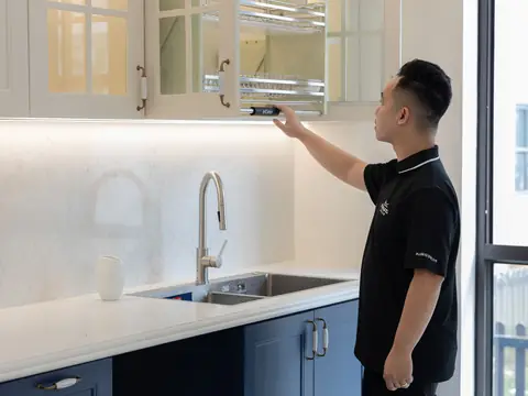 A worker adjusting a cabinet in a bright new kitchen