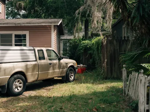 A pickup truck parked beside a house and a picket fence