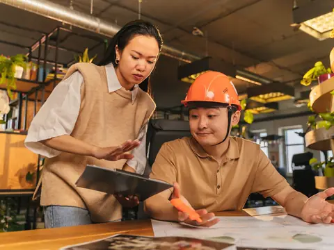 Two people going over plans and a tablet, one in a hard hat
