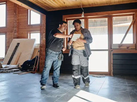 Two builders checking renovation plans on a tablet
