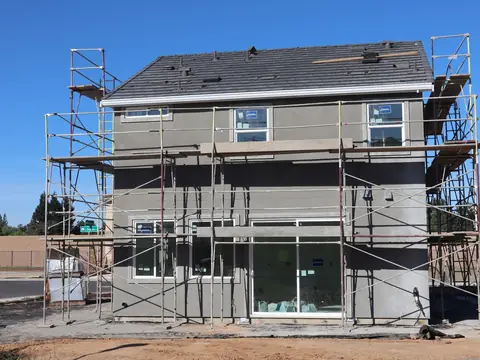 Scaffolding round a new two-story house on a sunny day