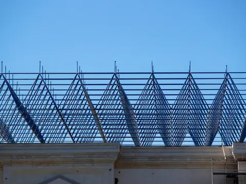 A steel roof frame rising against a clear blue sky