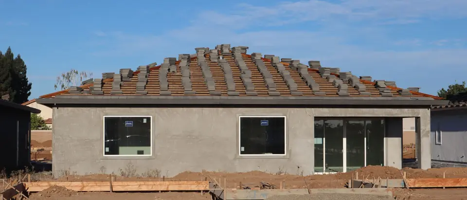 A new single-story house with its roof tiles stacked ready to lay