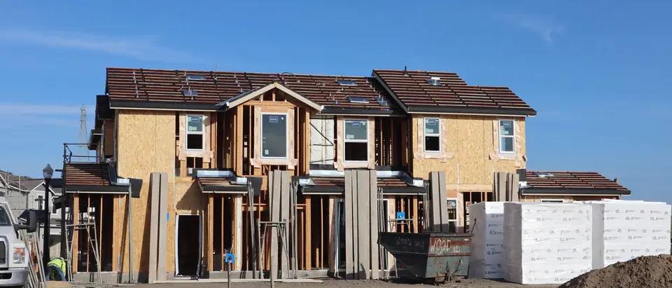 A row of new townhouses in their wood frames under a blue sky