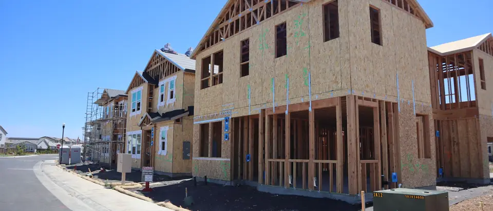 A street of new houses in their wood frames on a sunny day