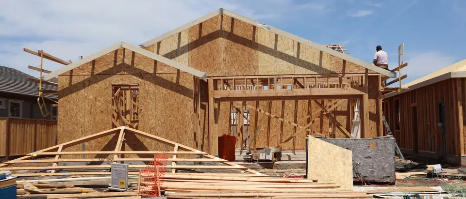 The wood frame of a new home going up under a blue sky