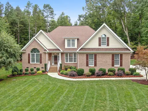 A brick home with a fresh green lawn and planted beds