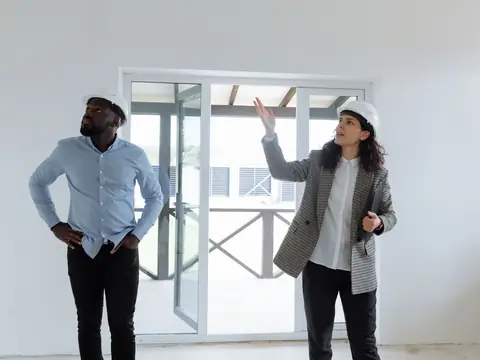 Two people in hard hats talking in a bright new room