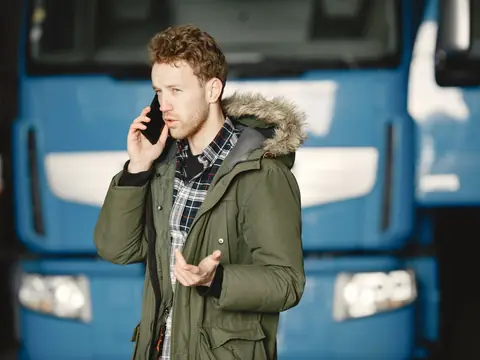 A man taking a phone call in front of a blue truck