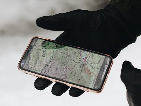 A gloved hand holding a phone with a map on the screen