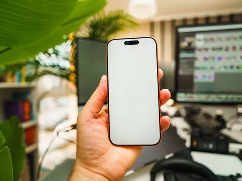 A hand holding up a phone at a desk