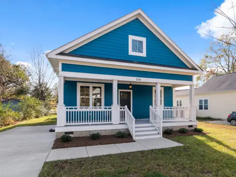 A freshly painted blue house with a white porch and railings
