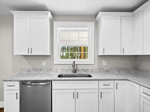 A bright kitchen with white cabinets and a granite counter