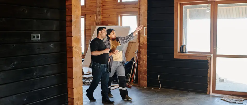 Two people talking through a renovation in a timber-lined room
