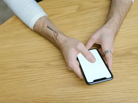 Hands using a phone on a wooden table